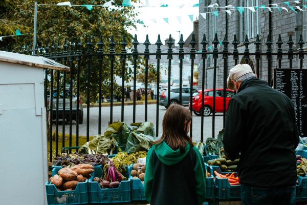 a man and a little girl standing in front of a fruit and vegetable stand